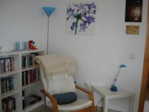 una habitación con una silla y una estantería con libros en Life Apartments Costa Ballena, en Costa Ballena