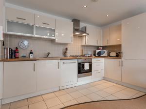 a white kitchen with white cabinets and appliances at Galician Shore in Poole