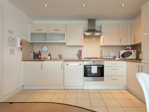 a kitchen with white cabinets and white appliances at Galician Shore in Poole