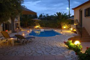 a swimming pool in a backyard at night with lights at Finikes Apartments in Stoupa
