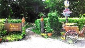 a garden with a bike and a sign and some bushes at At Home Sukhothai in Sukhothai