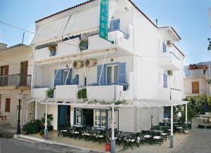 a white building with tables and chairs in front of it at Hotel Asteroa in Ancient Epidauros