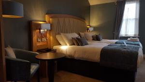 um quarto de hotel com uma cama grande e uma cadeira em The Bull & Stirrup Hotel Wetherspoon em Chester
