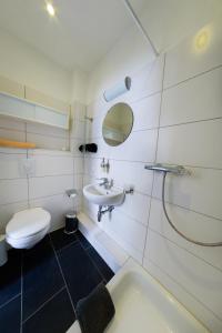 a white bathroom with a toilet and a sink at City Apartment Aurich - Ostfriesland in Aurich