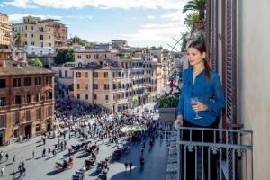 a woman standing on a balcony looking out over a city at The Inn at the Spanish Steps in Rome