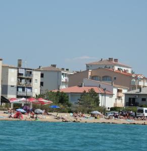 Grupa ludzi na plaży z parasolami w obiekcie Apartments Luna w mieście Pag