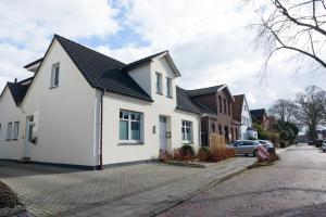 a white house with a black roof on a street at City Apartment Aurich - Ostfriesland in Aurich