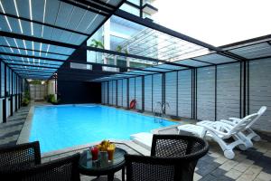 a large swimming pool with chairs and a table at Diana Heights Luxury Hotel in Nedumbassery