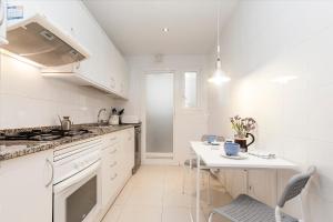 a white kitchen with a table and a stove at Mia Beach-City apartment in Montgat
