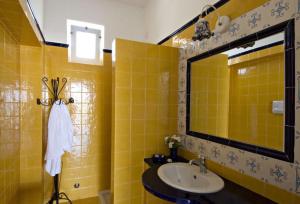 a yellow bathroom with a sink and a mirror at Hotel Girasole in Panarea