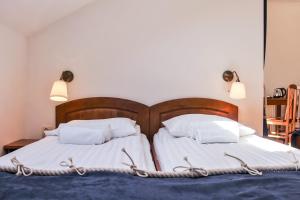 2 camas con sábanas blancas y almohadas en un dormitorio en Willa Bursztynowa, en Rewa