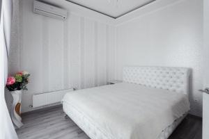 オデッサにあるCity Center Apartmentの白いベッドと花瓶が備わる白いベッドルーム1室