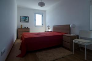 a bedroom with a red bed and a chair at Casa Rosa-Porto dos Carneiros in Lagoa