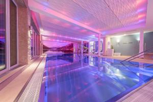 a swimming pool in a house with purple lights at Hotel Schönruh in Gerlos