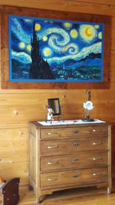 uma pintura numa parede acima de uma cómoda com uma cómoda em Chalet Il Fungo em Averara