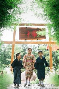 Eine Frau und zwei Kinder stehen vor einem Schrein in der Unterkunft Zen Villa Khao Yai in Mu Si