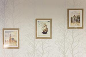three framed pictures on a wall with trees at Hostel Universus in Gdańsk