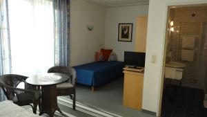 Schlafzimmer mit einem blauen Bett, einem Tisch und einem Schreibtisch in der Unterkunft Pension Dreiländerblick in Bad Gleichenberg
