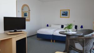 a room with a bed and a desk with a television at Pension Dreiländerblick in Bad Gleichenberg