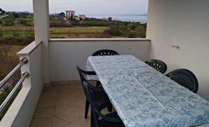 a table and chairs on a balcony with a view of the ocean at Apartmani Mihaela Dobropoljana 52 in Dobropoljana