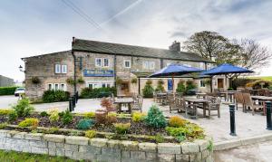 a inn with tables and umbrellas in a garden at The Alma Inn in Colne