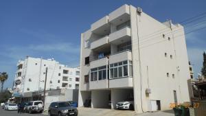 a white building with cars parked in front of it at Sea Anemone Apartments in Paphos City