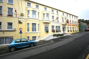 a blue car parked in front of a yellow building at Dorrians Imperial Hotel in Ballyshannon