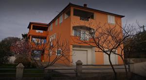ein großes orangefarbenes Gebäude mit einer weißen Garage in der Unterkunft Apartmani Mihaela Dobropoljana 52 in Dobropoljana