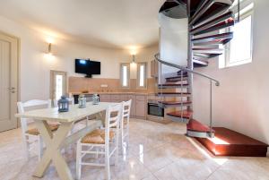 a dining room with a table and chairs and a spiral staircase at Monolithia in Kamari