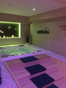 uma banheira de hidromassagem num quarto com iluminação roxa em Aux 5 Sens em Tillé