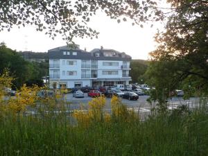a large white building with cars parked in a parking lot at Hotel Conde in Taboadela
