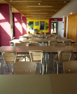 an empty classroom with tables and chairs and purple walls at Albergue Montes de Anaga in El Bailadero