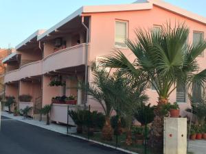 um edifício rosa com palmeiras em frente em Familien Apartment Zeno em Ulcinj
