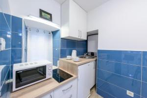 een kleine keuken met een magnetron en blauwe tegels bij Apartman Gloria in Dubrovnik