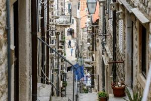 een steegje in een oude stad met mensen die er langs lopen bij Apartman Gloria in Dubrovnik