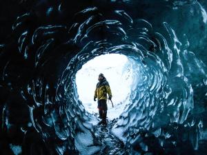 un hombre caminando por una cueva de hielo en Volcano Hotel, en Vík