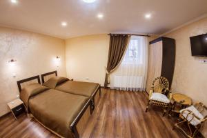 a bedroom with a bed and a television and wooden floors at Panorama Apart-Hotel in Kamianets-Podilskyi