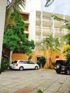 dos autos estacionados en un estacionamiento frente a un edificio en Hotel Flamingos Colima, en Colima