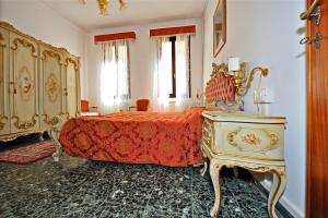 a bedroom with a bed with a red bedspread and a table at Venice San Leonardo in Venice