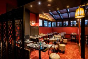 a restaurant with red walls and tables and chairs at Maison Grecque Hotel Extraordinaire in Patra