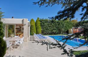 uma villa com uma piscina, uma mesa e cadeiras em Villa EverGreen em Foinikiá