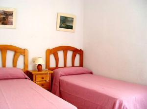 sypialnia z 2 łóżkami z różową pościelą i szafką nocną w obiekcie Apartamentos los Boliches w mieście Puerto de Mazarrón