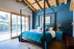 Dormitorio azul con cama y ventana grande en Chalet Alexandra en Les Houches