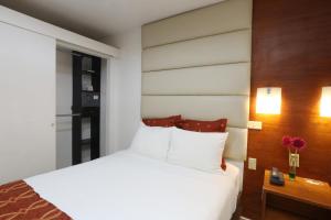 1 dormitorio con cama blanca y pared de madera en Minister Business Hotel, en Tegucigalpa