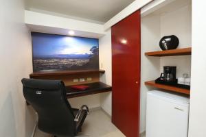 Habitación con silla y TV en la pared. en Minister Business Hotel, en Tegucigalpa