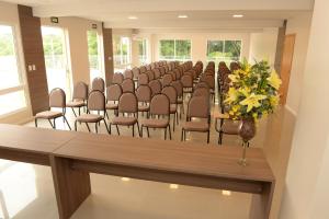 a room with a row of chairs and a vase with flowers at Hotel Solar do Parque in Tabapira