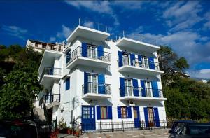 a tall white building with blue shutters on it at Syraina Apartments in Skiathos Town