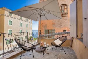 a patio with two chairs and an umbrella on a balcony at U Palazzu Ghejenuvese in Bastia