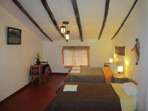 una camera d'albergo con due letti e un tavolo di Killari B&B a Ollantaytambo