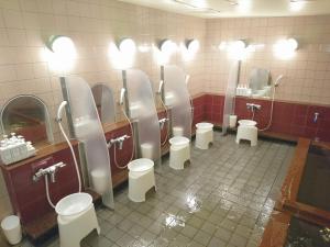 ein Badezimmer mit einer Reihe von Urinalen und WCs in der Unterkunft Atsugi Capsule Hotel in Atsugi